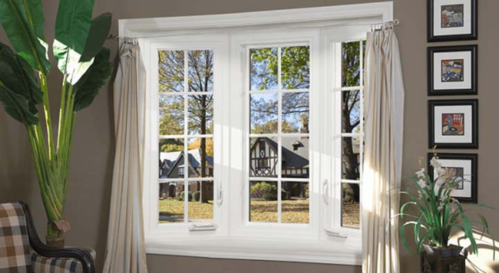 A window with curtains and blinds in front of trees.