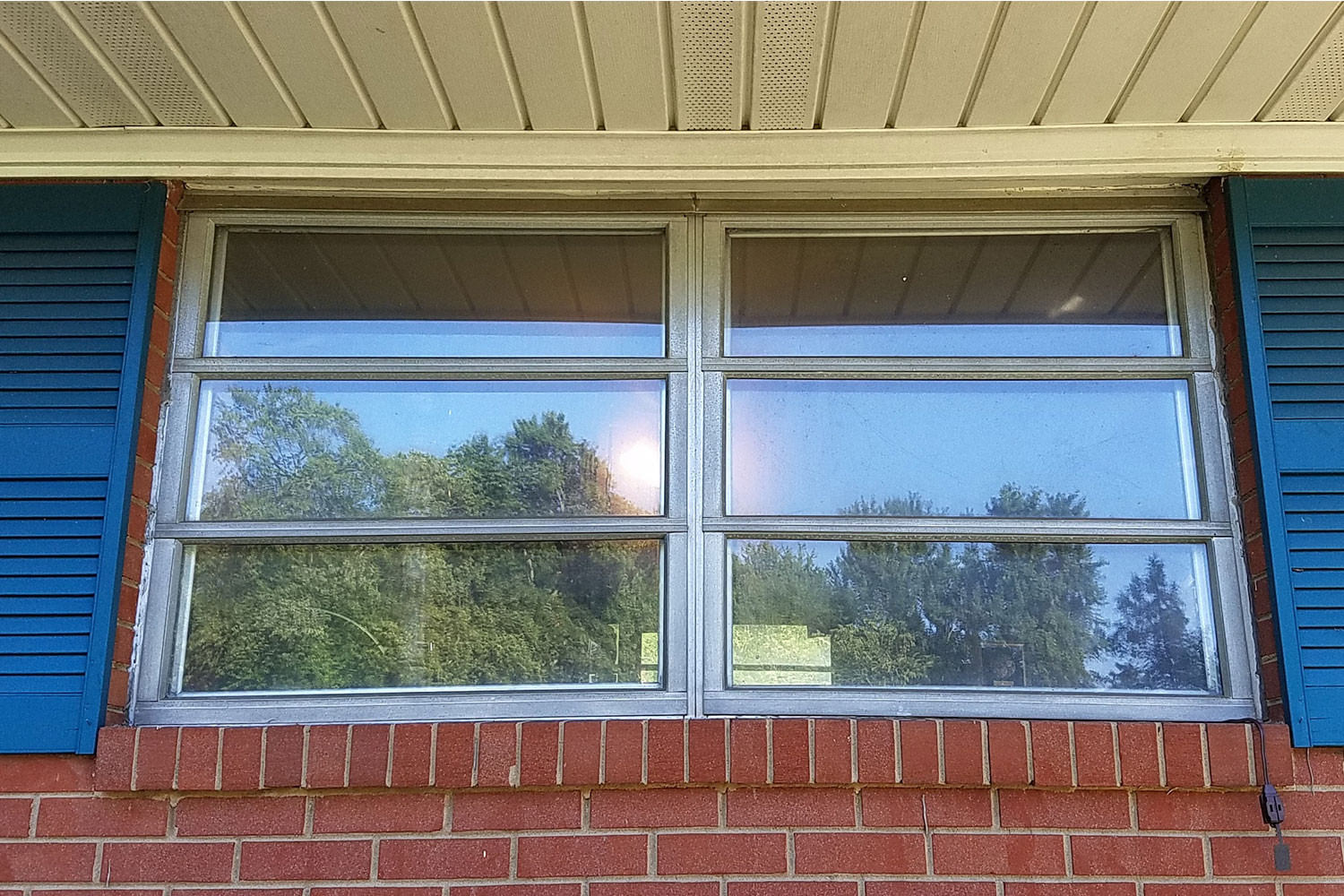 A window of a house from the outside with the reflection of trees