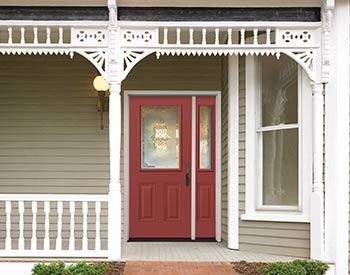 A red door is in front of the porch.