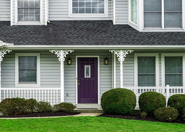 A house with light gray walls and deep purple door